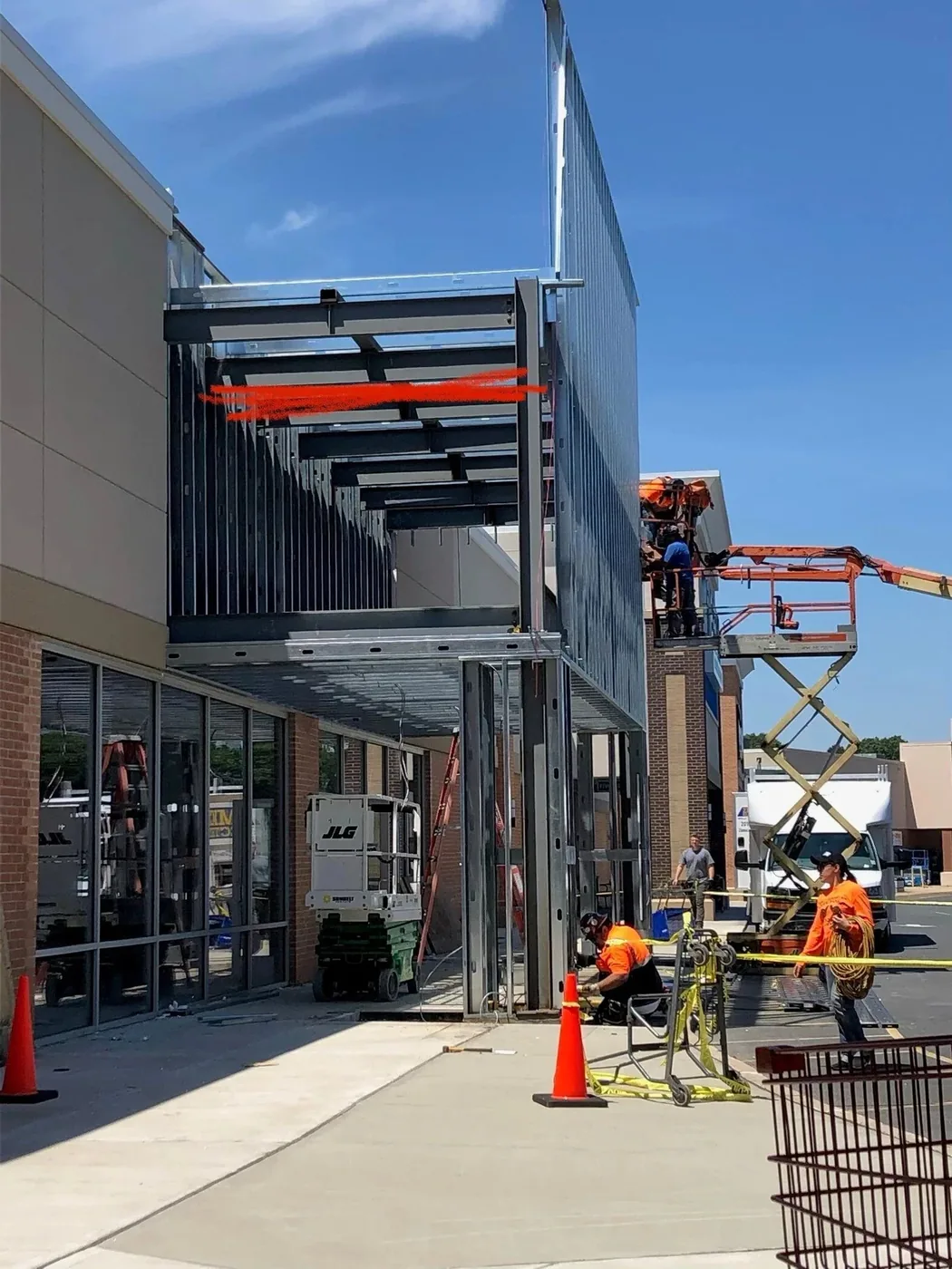 Crew on a scissor lift performing exterior facade and canopy electrical work at a retail center