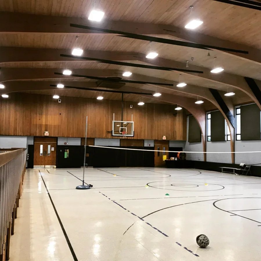 Community gymnasium with barrel-vault wood ceiling and new recessed LED downlighting